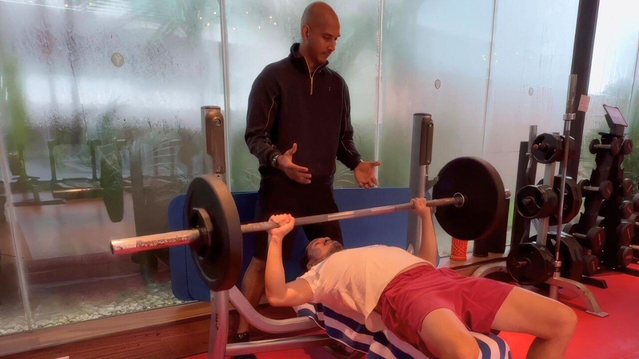Personal trainer helping to spot a client on the bench press
